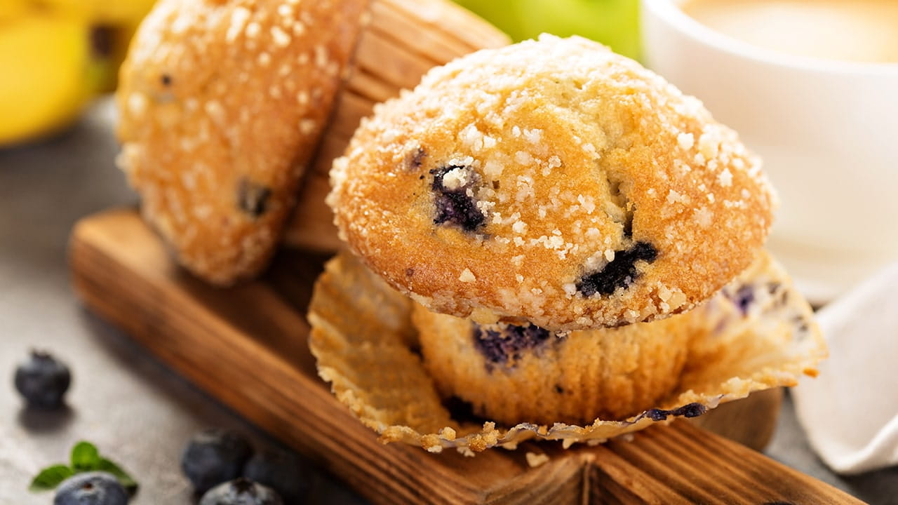Blueberry muffin with sugar topping on a wooden board.