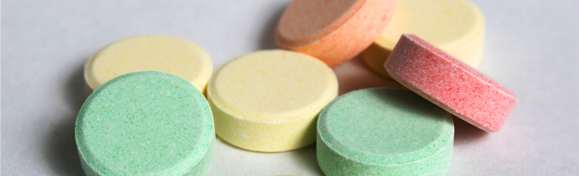 Stacked pastel-colored round tablets on a light surface.