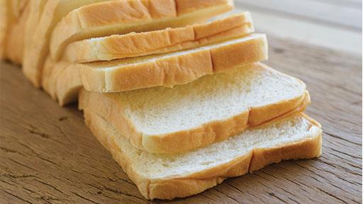 Slices of white bread fanned out on a wooden surface.