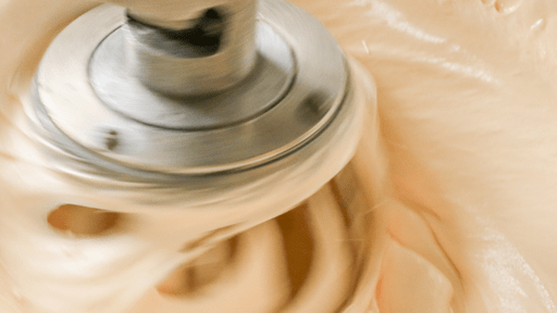 An electric mixer mixing egg batter in a metal bowl