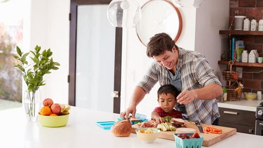 Photo of a father and son in a kitchen preparing sandwiches.