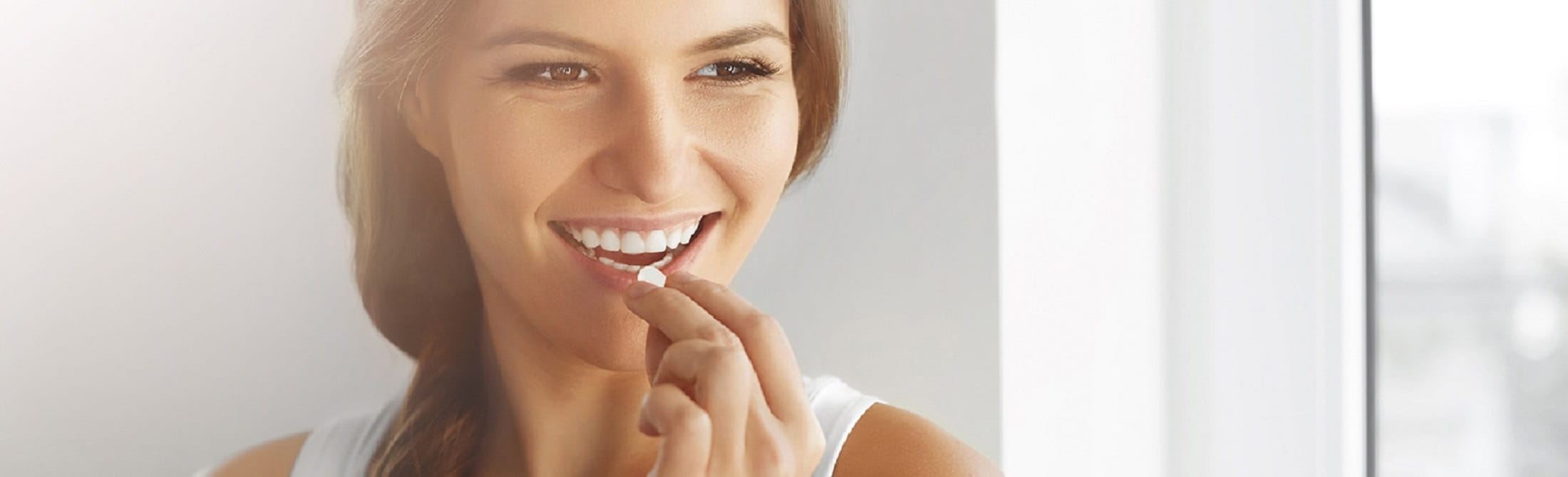 Person in white top near window with face blurred.