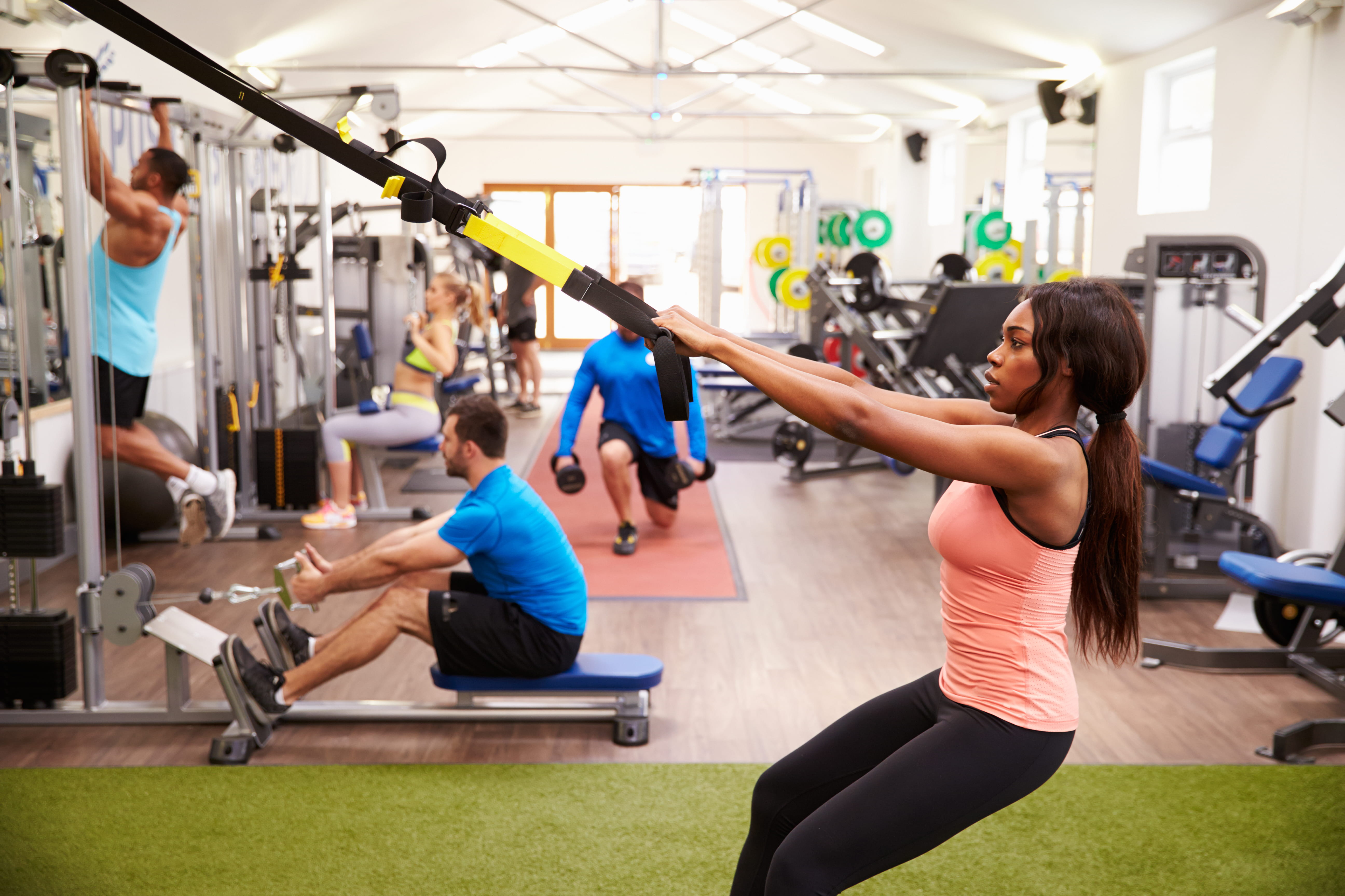 Photo of men and women performing exercises together inside of a gym.
