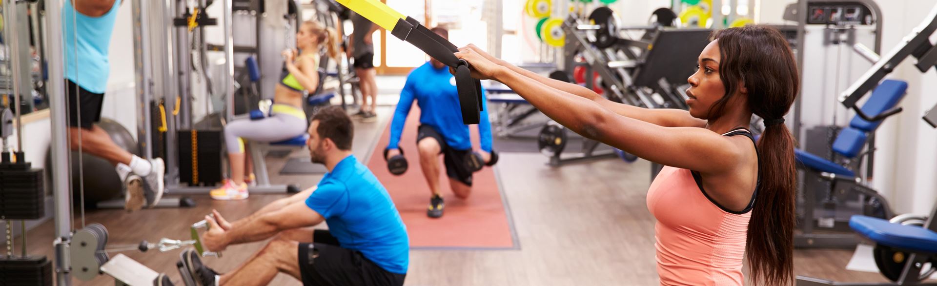 Photo of men and women performing exercises together inside of a gym.