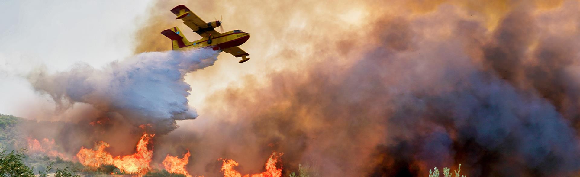 Firefighting aircraft dropping water over wildfire