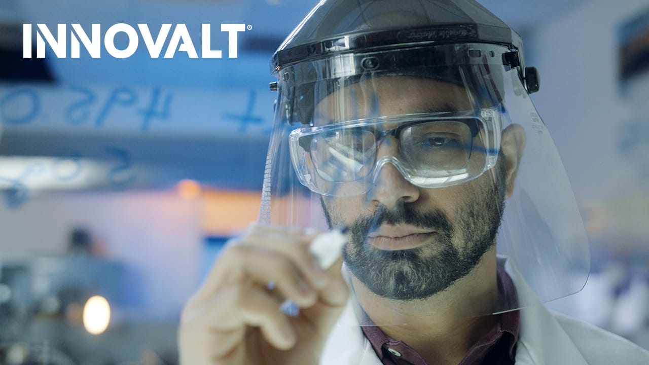 Person in face shield holding marker with INNOVALT text.