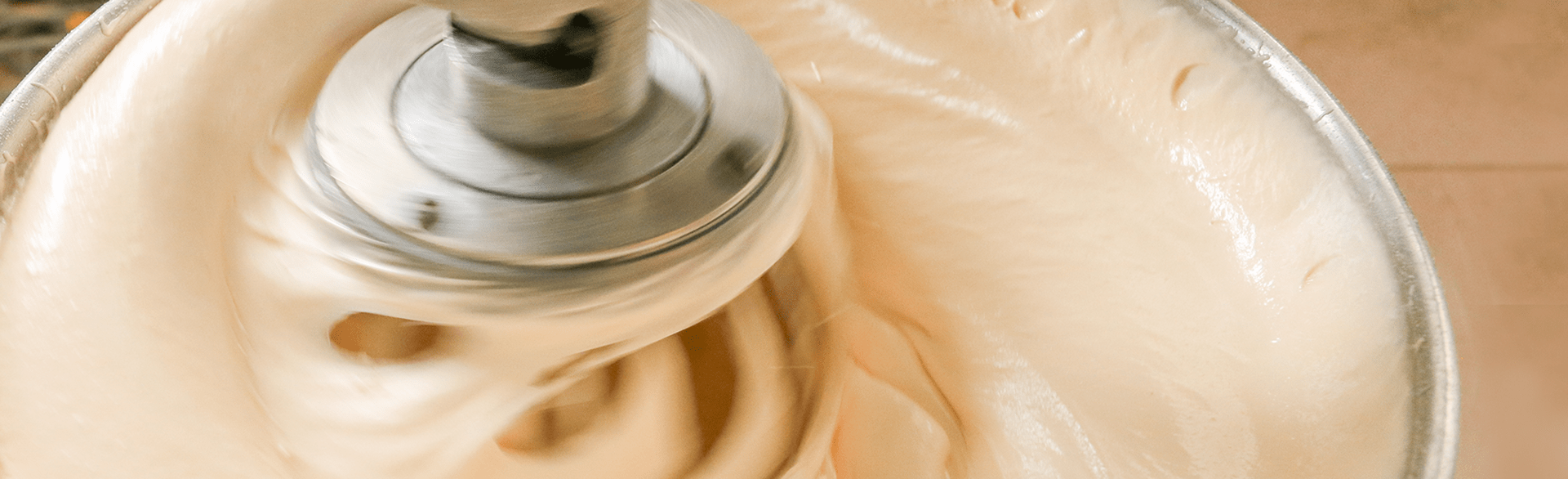 An electric mixer mixing egg batter in a metal bowl