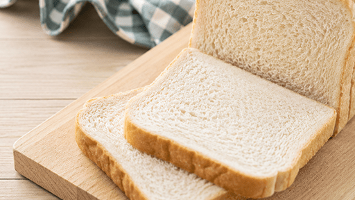 Sliced white sandwich bread loaf on a wooden cutting board.