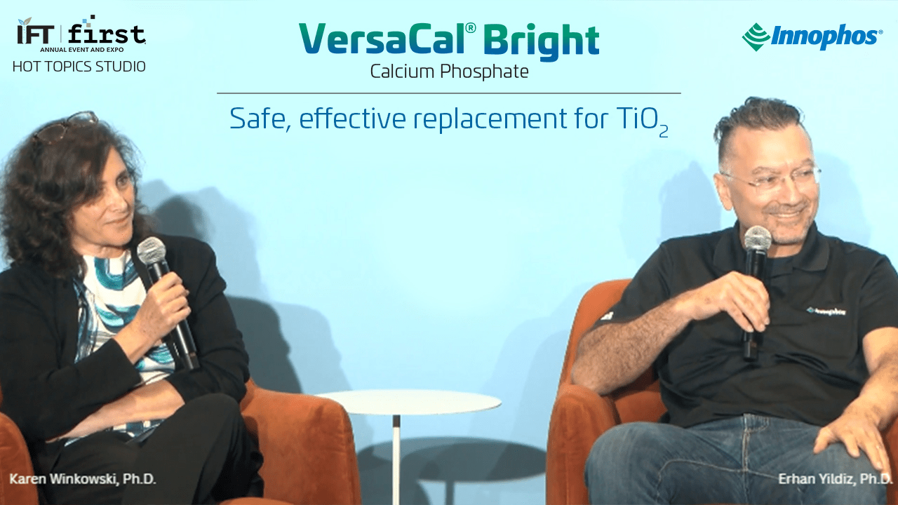 Two people seated with microphones in front of a VersaCal® Bright Calcium Phosphate backdrop.
