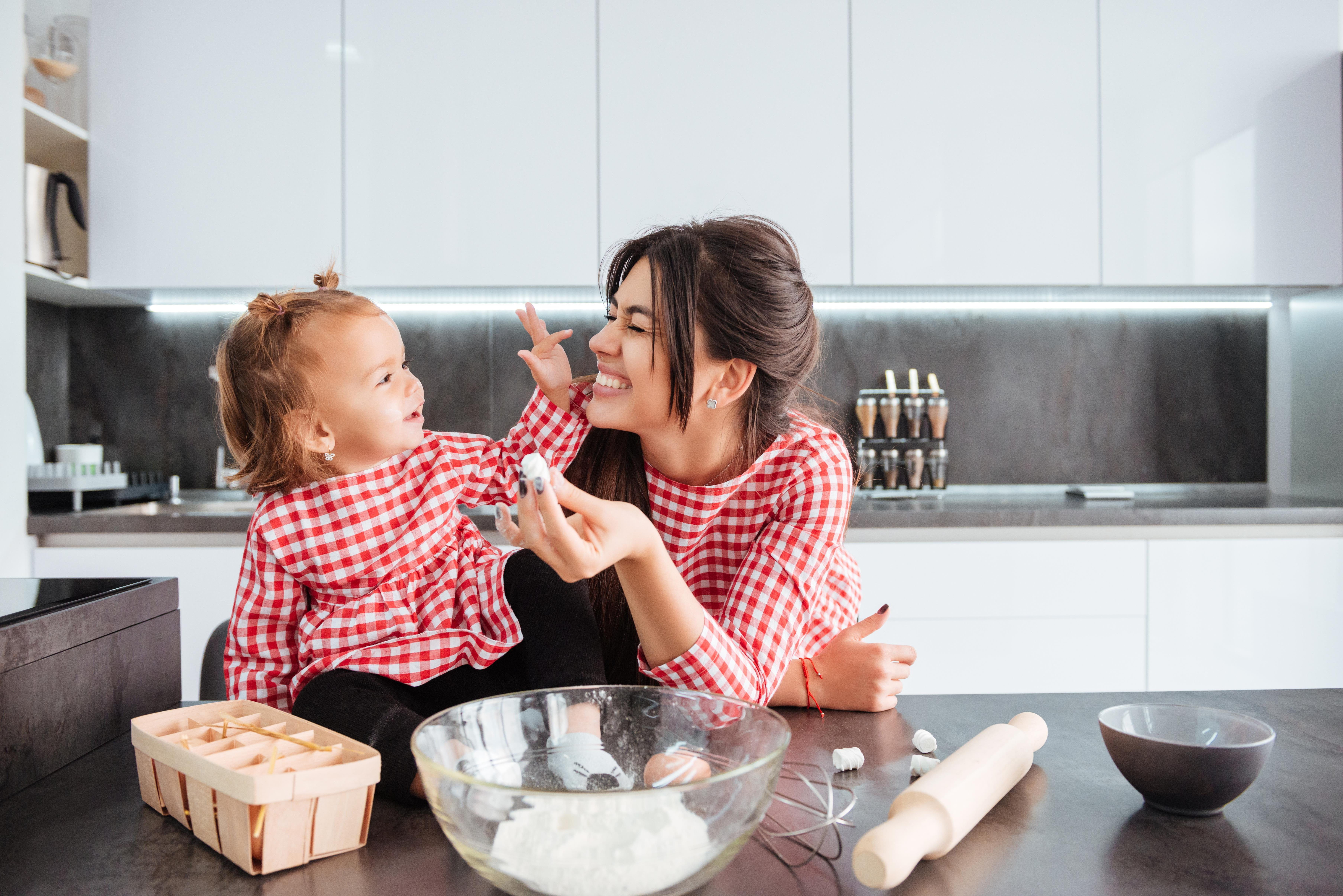 Two people in a kitchen holding dough with baking items on the counter