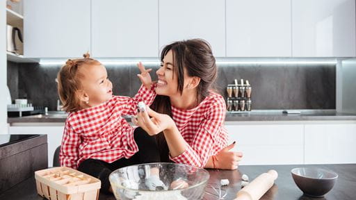 Two people in a kitchen holding dough with baking items on the counter