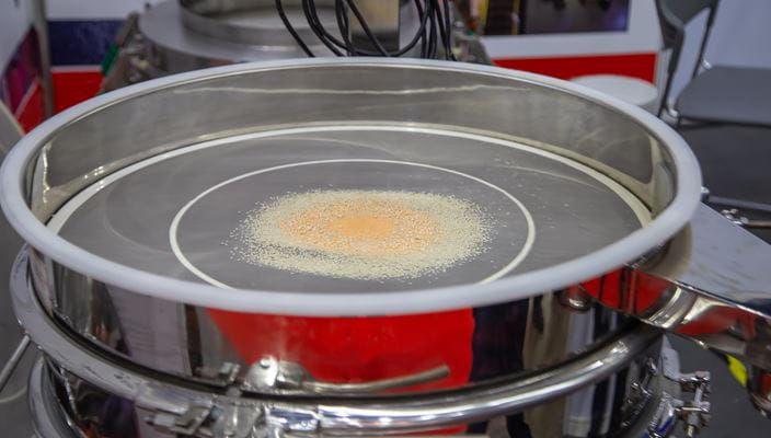 Metal industrial sieve with granular material in the center and connected cables