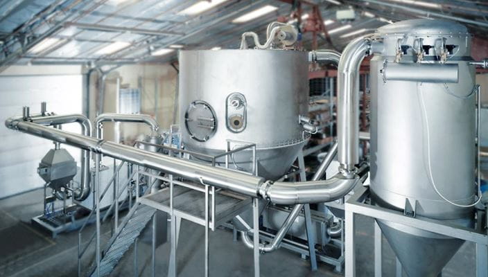 Industrial setup with metal tanks, pipes, and machinery in a processing plant