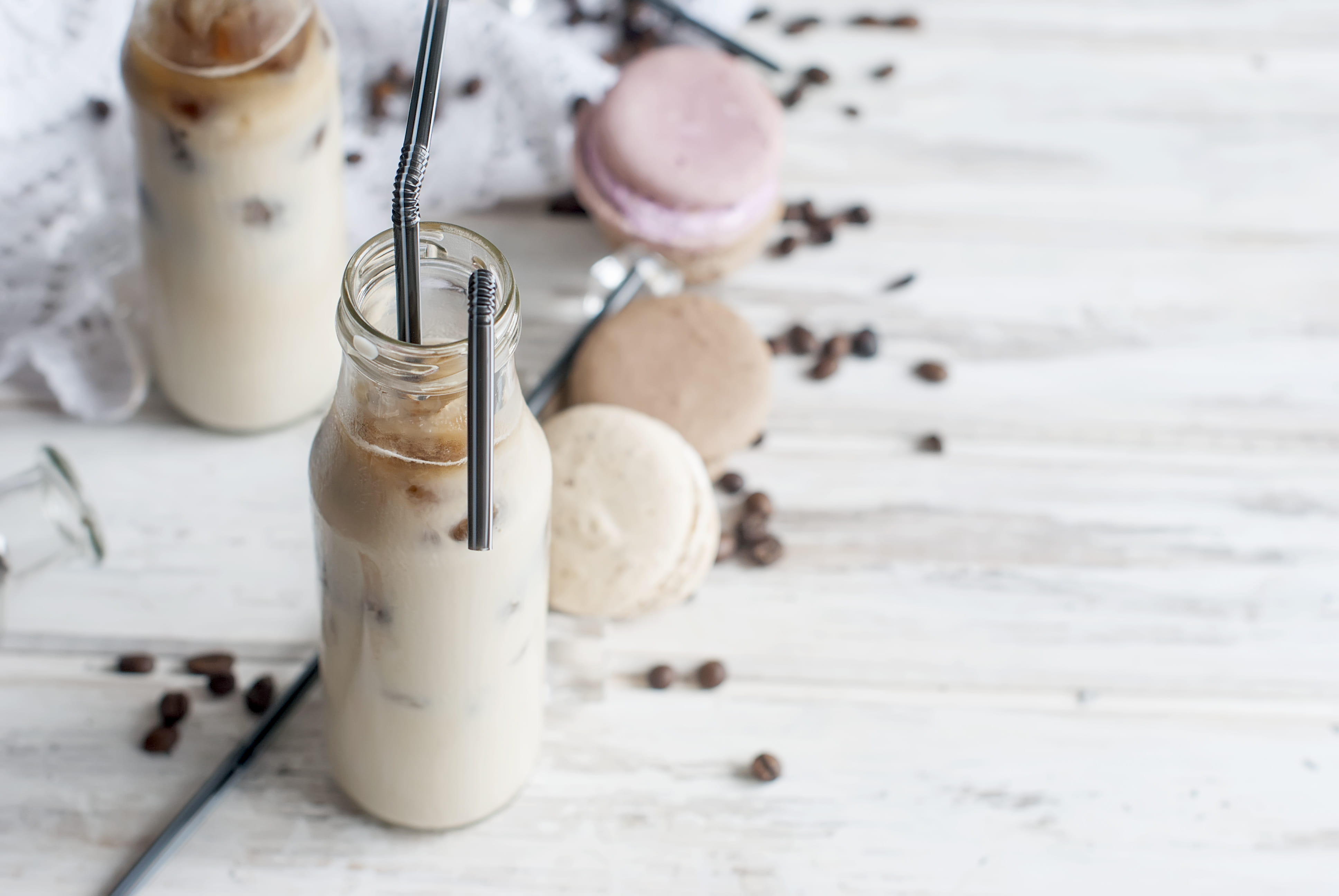 Photo of a creamy beverage with straws surrounded by macarons.