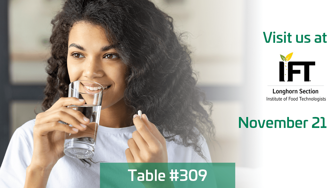 A woman holding a pill drinking water