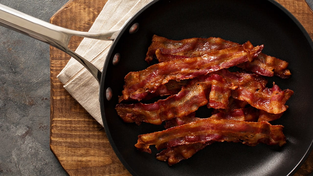 Bacon on a pan placed on a platter covered with a towel