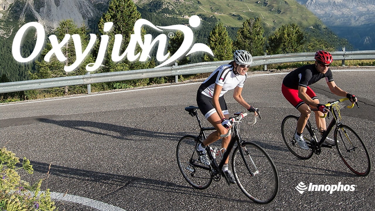 Cyclists on a mountain road with Oxyjun and Innophos logos.